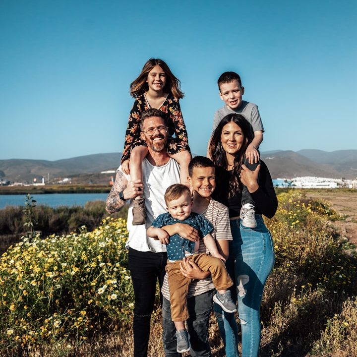 2 women and man standing on green grass field during daytime